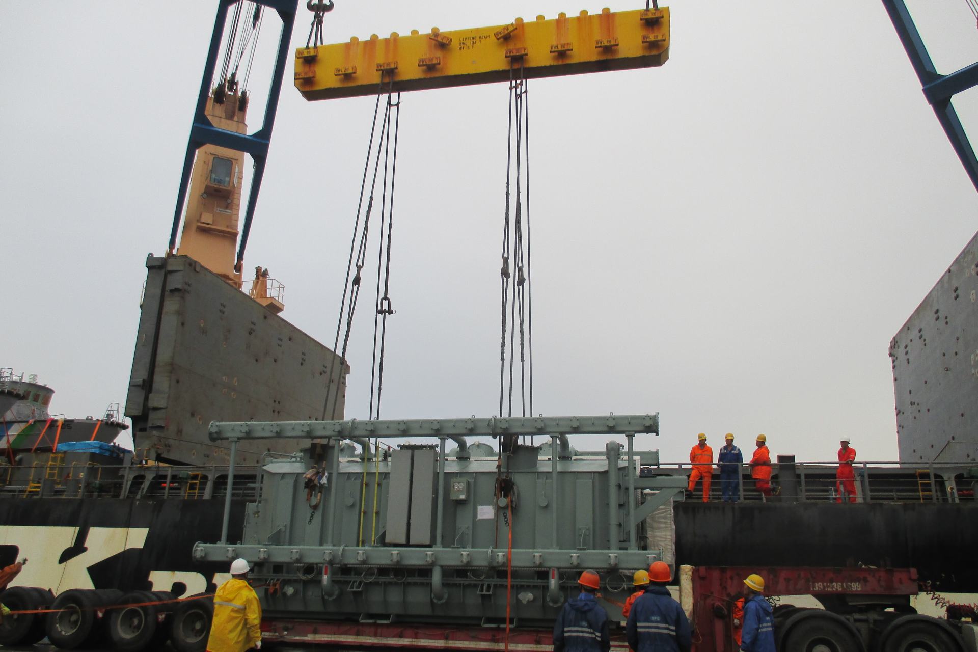 Cargo being transported from land to shipping vessel by crane and machinery